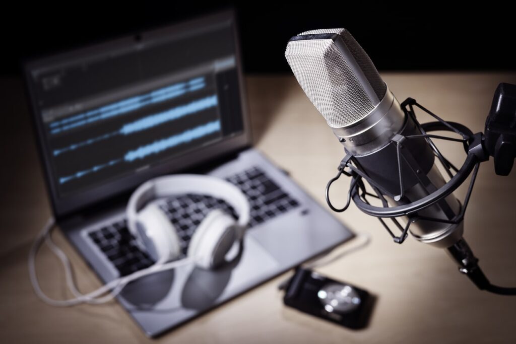 a picture of a podcast microphone, headphones and a laptop